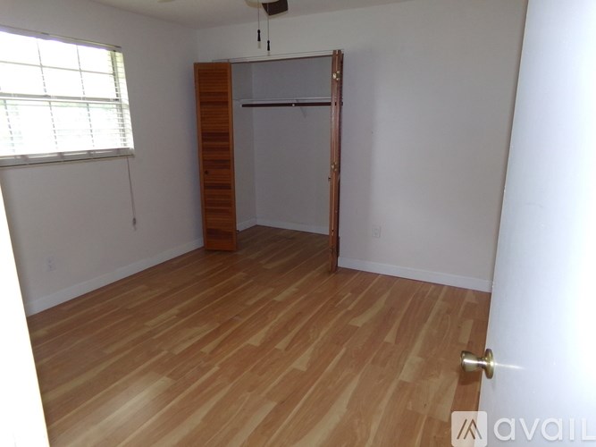 A room with wooden flooring and a white wall with a door and a window.