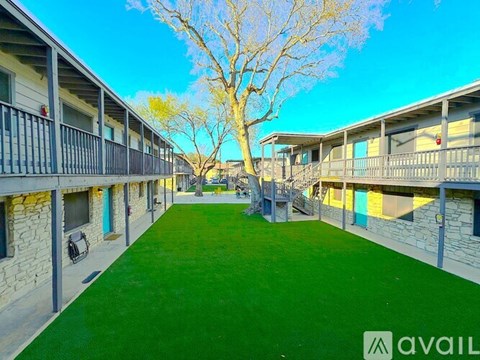 A tree in front of apartment buildings with a walkway in the middle.