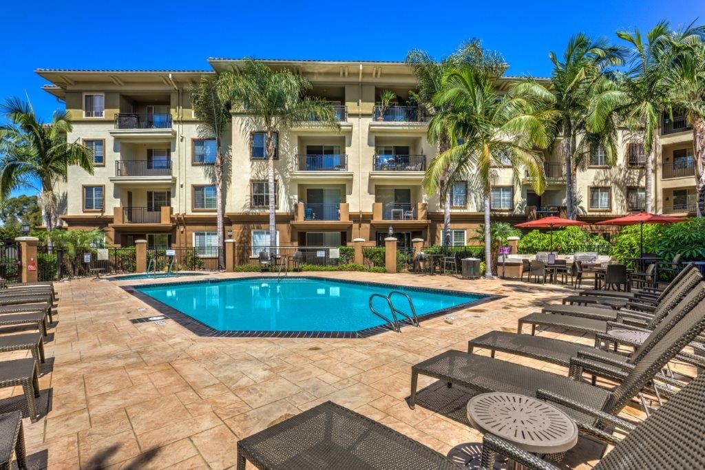 a large swimming pool in front of a hotel with palm trees