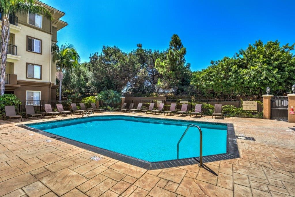a swimming pool with chairs around it in front of a building
