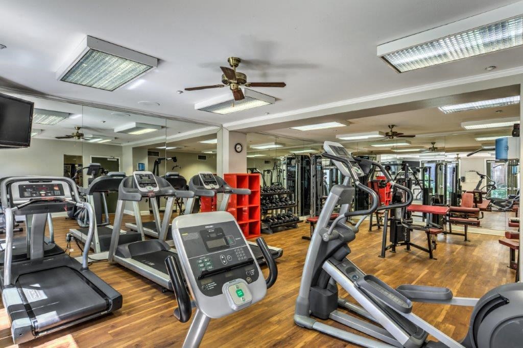 a gym with cardio equipment and a ceiling fan