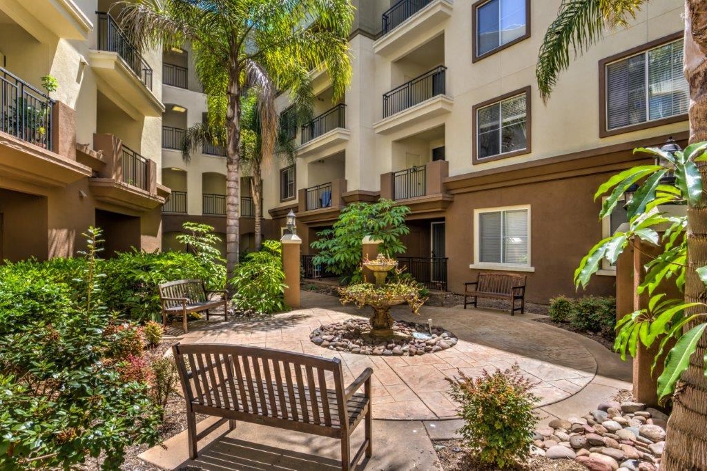 a courtyard with a fountain and benches in front of an apartment building