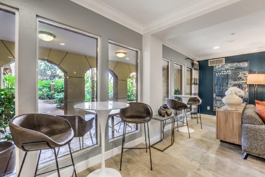 a living room with chairs and a table and windows