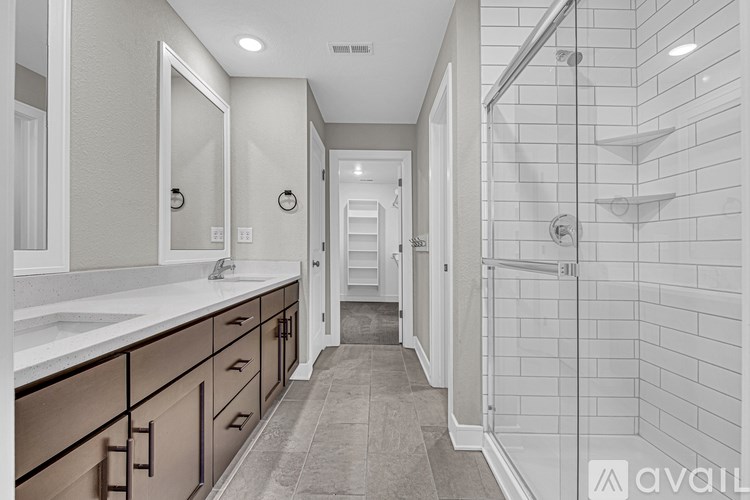 A bathroom with a walk-in shower and double sinks.