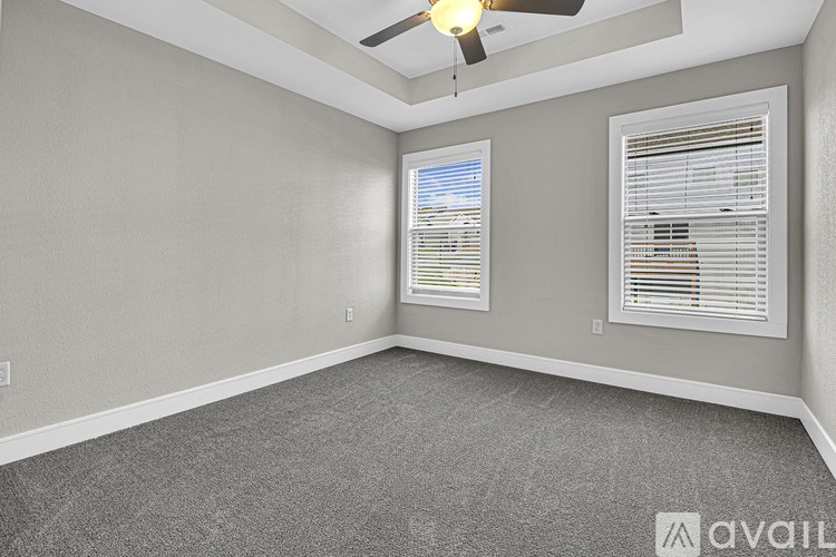 A room with a ceiling fan and two windows.