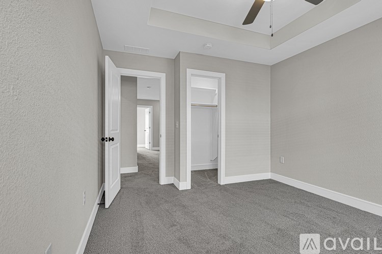 A spacious room with a carpeted floor and a ceiling fan.