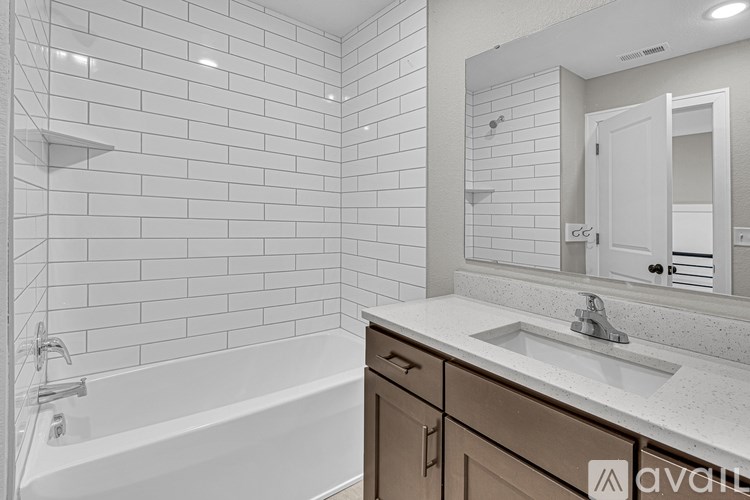 A white tiled bathroom with a bathtub, sink, and mirror.