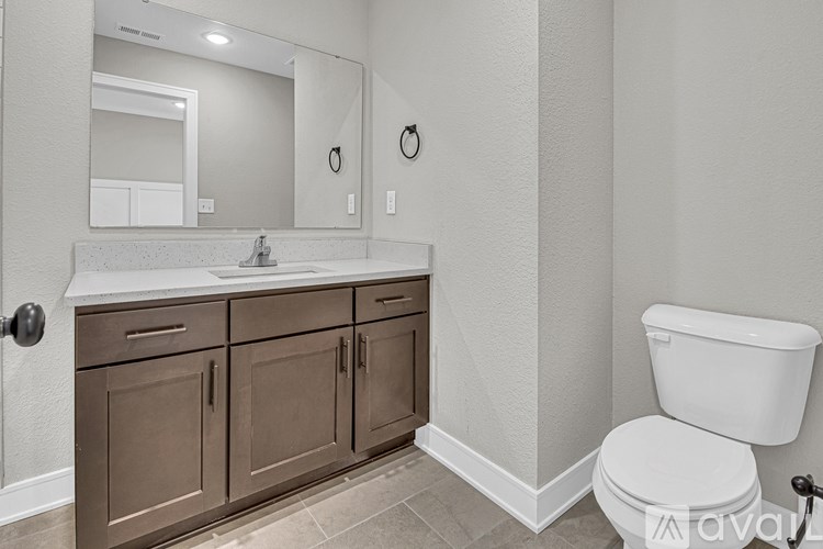 A bathroom with a white toilet and brown cabinets.