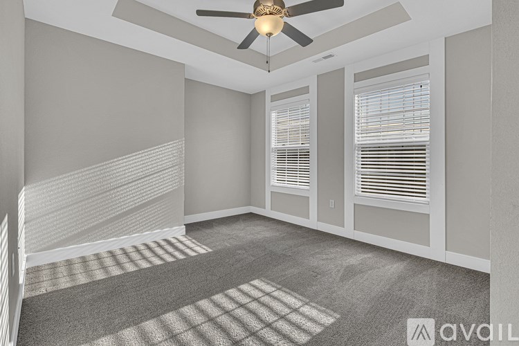 A room with a ceiling fan and carpeted floor.