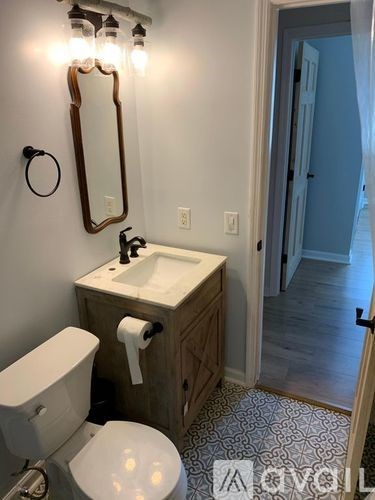 A bathroom with a toilet, sink, mirror, and lights.
