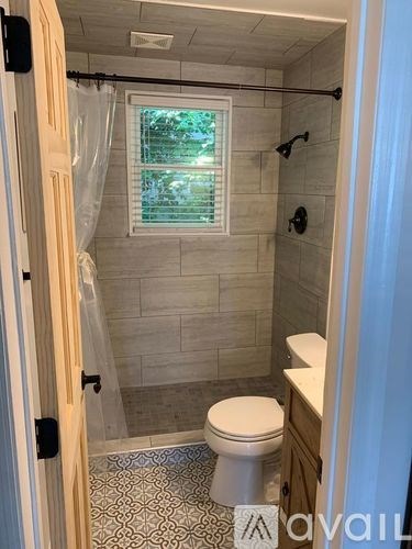 A bathroom with a toilet, a shower, and a window.