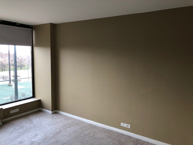 A room with a large window and a view of a green area outside.