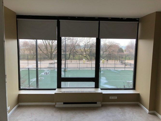 A room with a large window overlooking a tennis court.