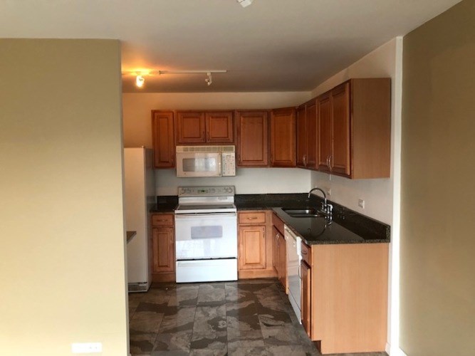 A kitchen with wooden cabinets and a white oven.