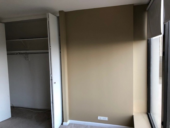 A room with a white door and a wall with a small white box on it.