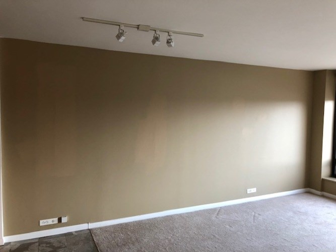 A room with a carpeted floor and a wall-mounted light fixture.