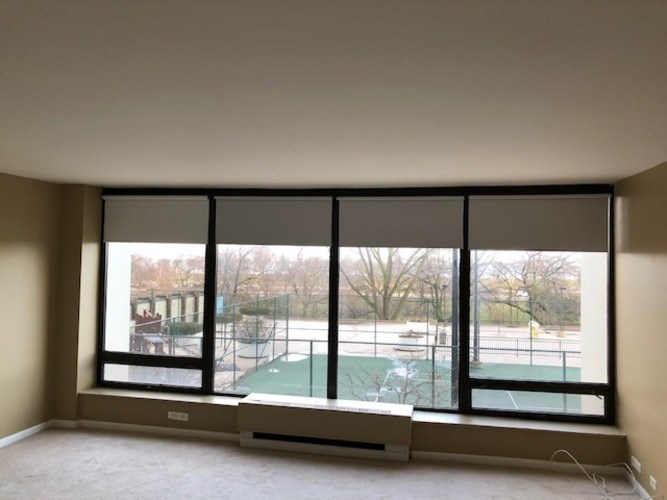A room with a large window overlooking a tennis court.