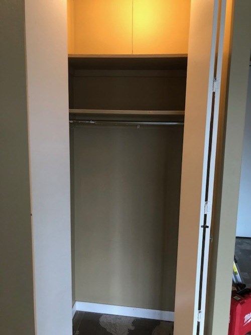 A small, dark refrigerator is in a narrow space.