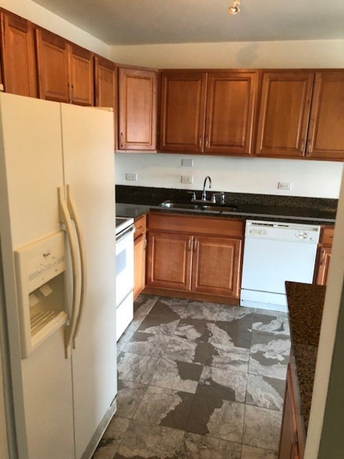 A kitchen with a white fridge and brown cabinets.