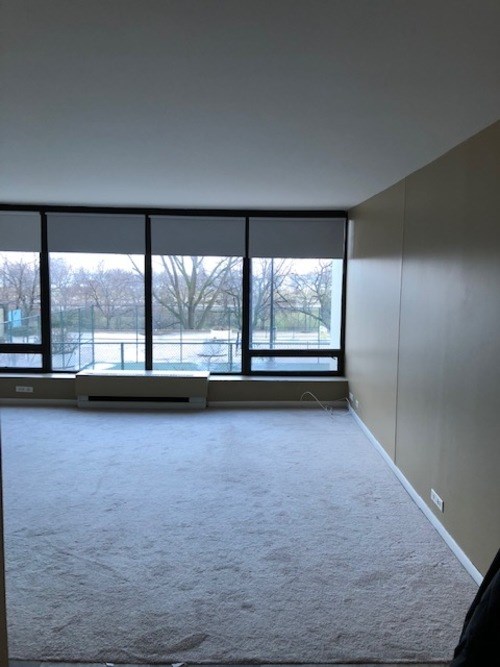 A room with a large window and a carpeted floor.