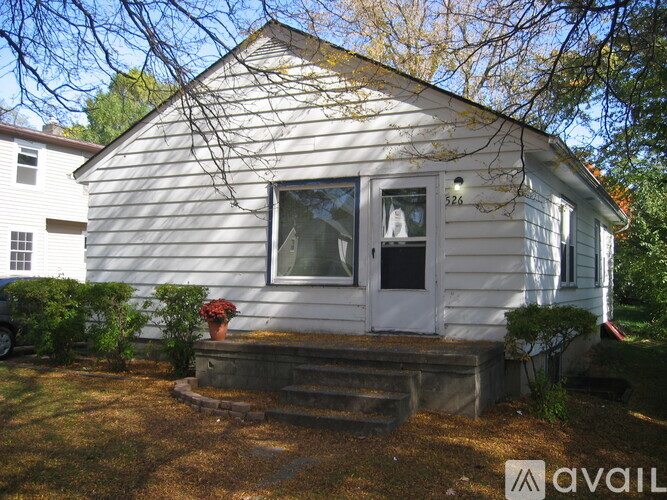 A small white house with a porch and a window.