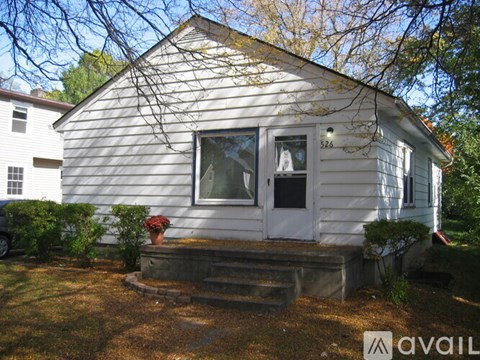A small white house with a porch and a window.