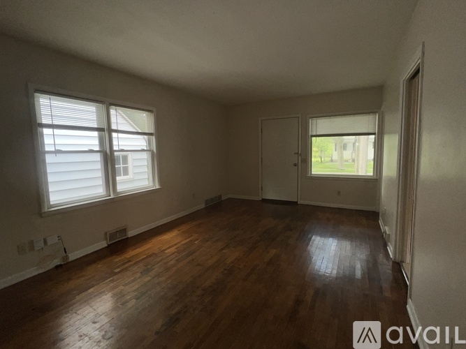 A room with wooden floors and a window with blinds.