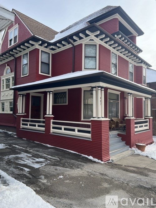 A red house with a white porch and snow on the ground.