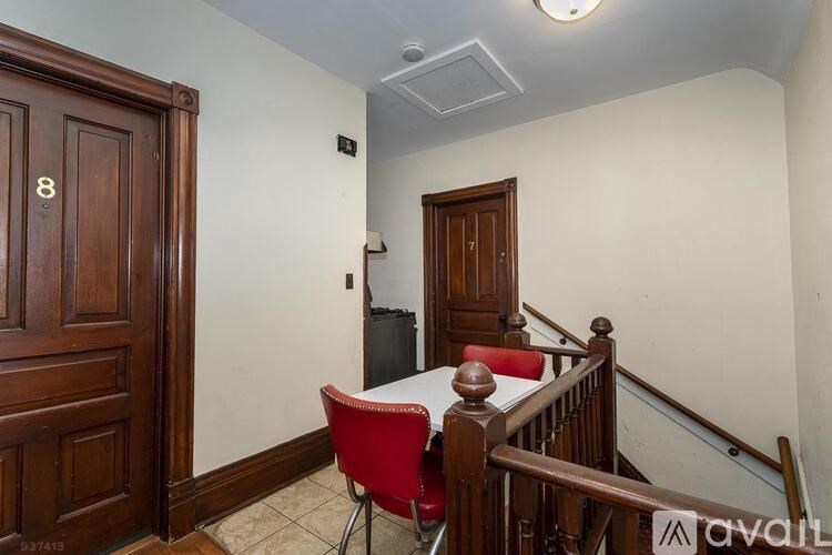 A room with a wooden door, a red chair, and a staircase.