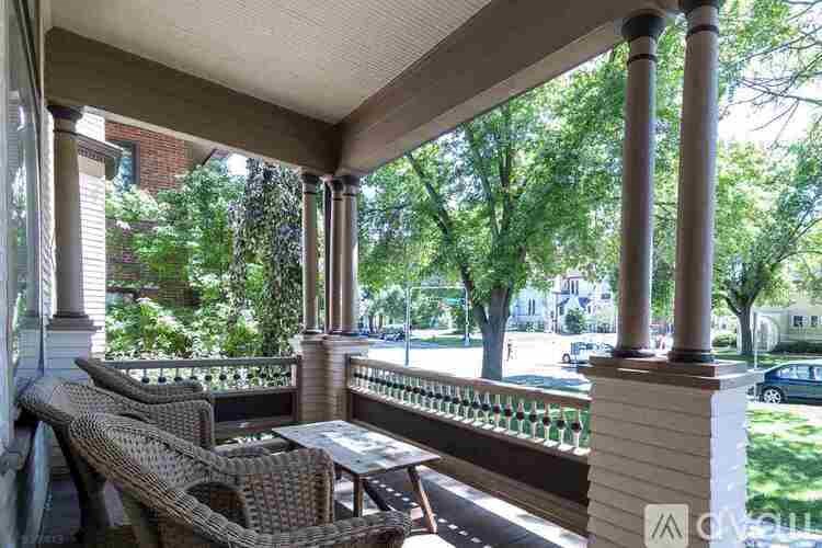 A porch with a table and chairs is surrounded by trees.