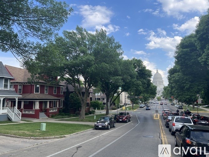 A street view with cars parked on the side and a large building in the distance.