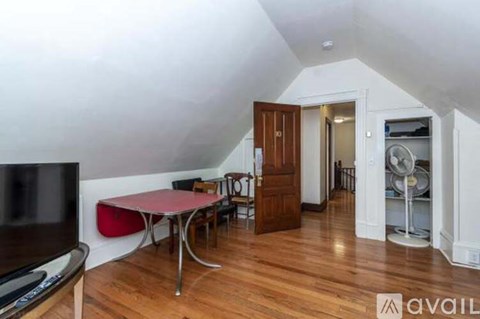 A living room with a television, a table and chairs, and a fan.