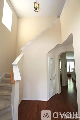 A hallway with a staircase and a doorway leading to another room.
