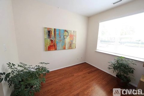 A room with a painting on the wall and a window letting in light.