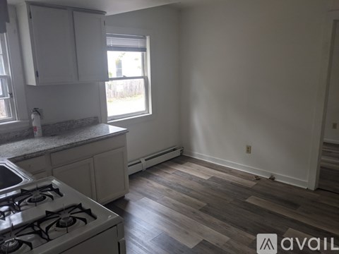 A kitchen with a white stove and wooden floors.