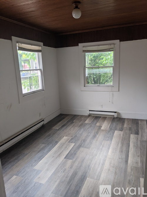 A room with wooden floors and two windows.