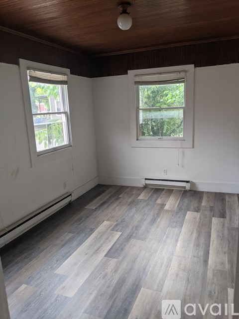 A room with wooden floors and two windows.