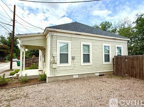 A small house with a porch and a fence in front.