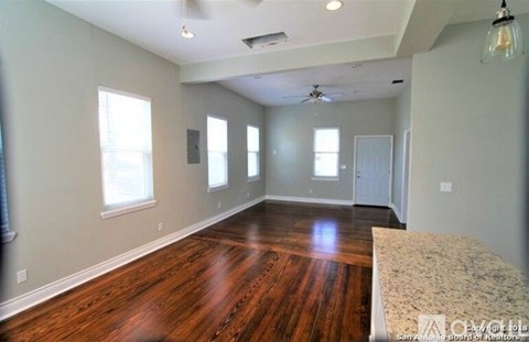 A spacious room with wooden floors and a ceiling fan.