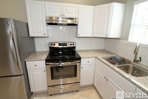 A kitchen with white cabinets and a stainless steel refrigerator.