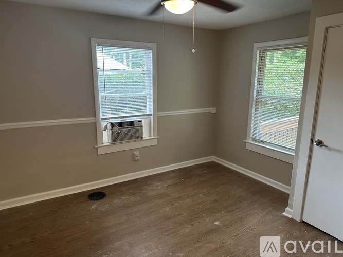 A room with a ceiling fan and two windows.