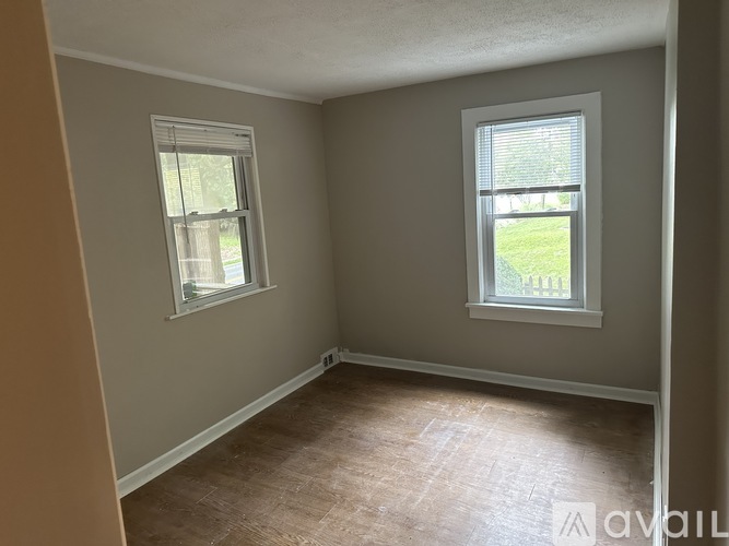 A room with two windows and a wooden floor.