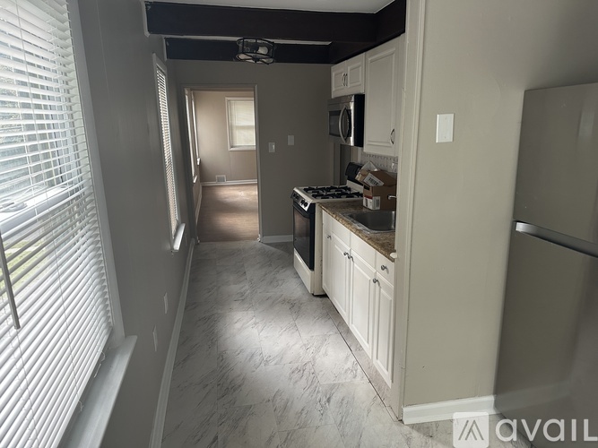 A kitchen with white cabinets and a marble floor.