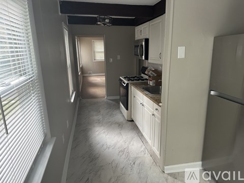 A kitchen with white cabinets and a marble floor.