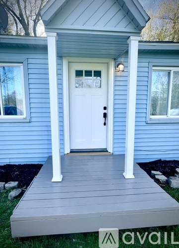 A small blue house with a white door and a porch.