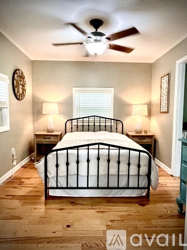 A bedroom with a bed, two lamps, and a ceiling fan.