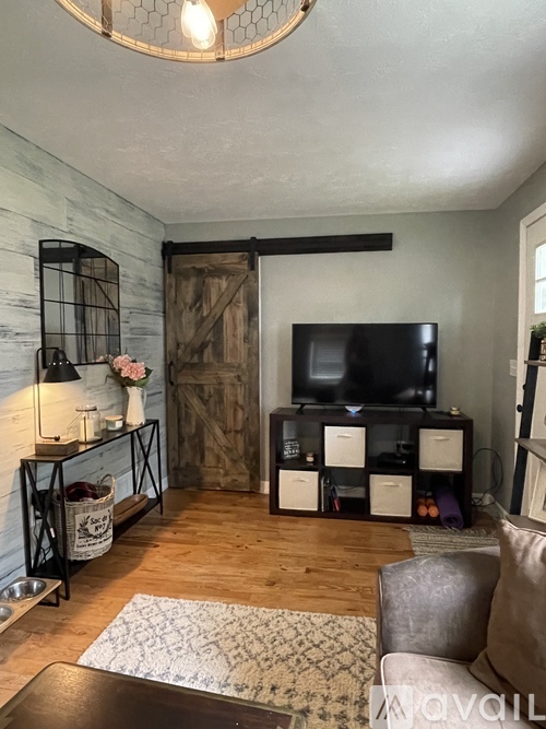 A living room with a wooden floor and a television on a stand.