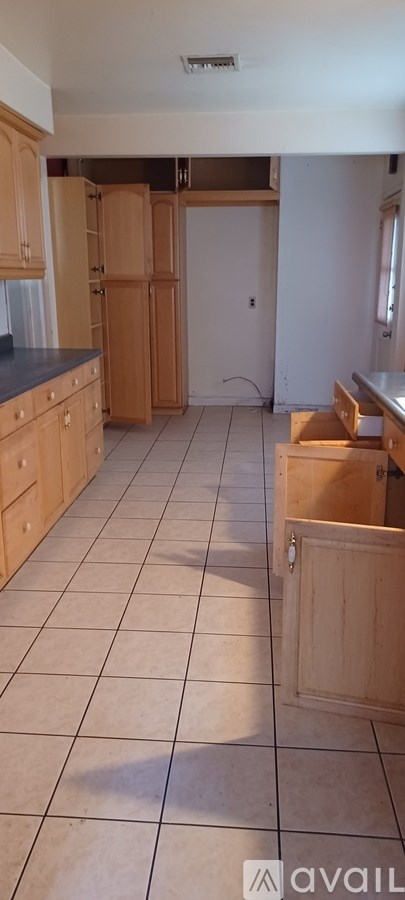 A kitchen with wooden cabinets and a tiled floor.