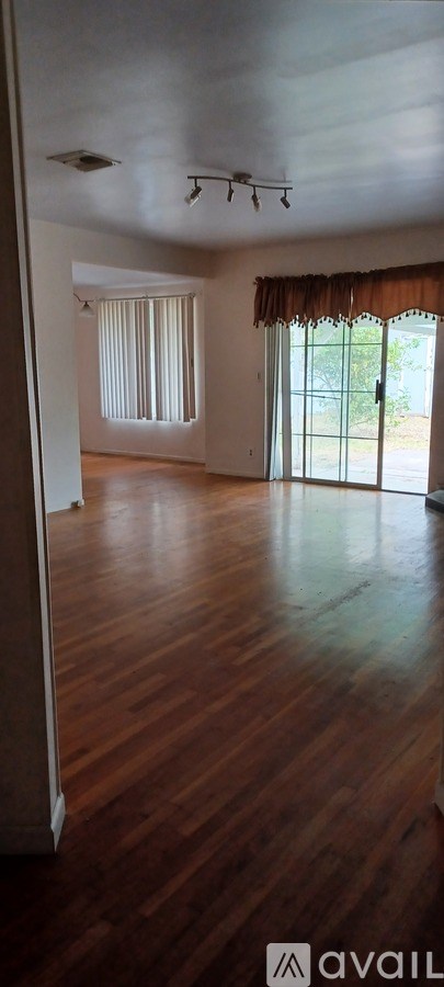 A room with wooden floors and a window with curtains.