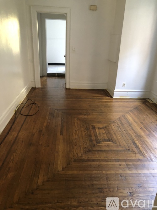 A room with wooden floors and a doorway leading to another room.